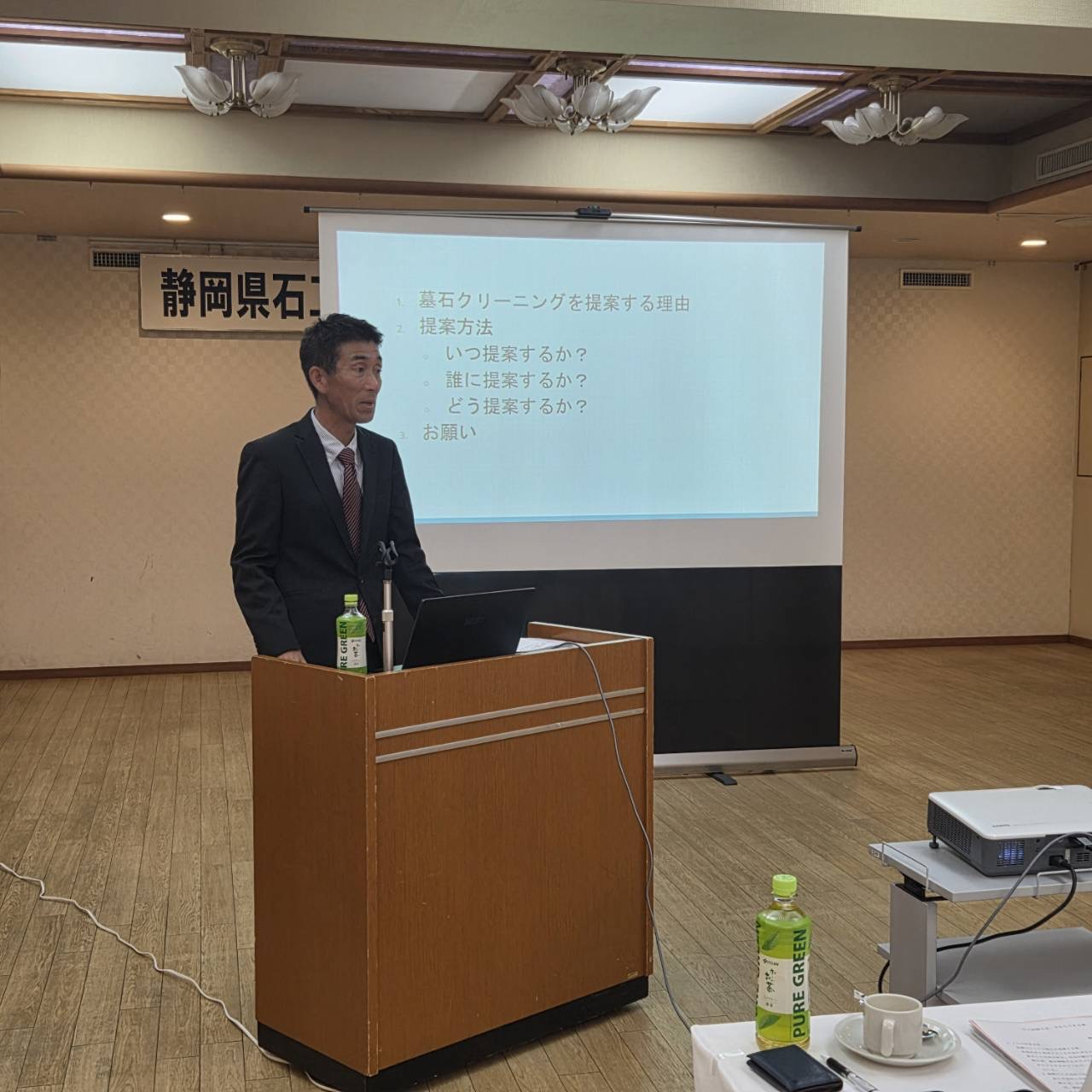 大勢の石材店経営者を前に墓石クリーニングについて講習する永野恵介